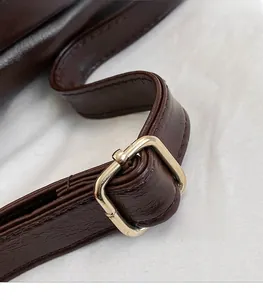 Close-up of dark brown leather strap with adjustable gold-tone square metal buckle