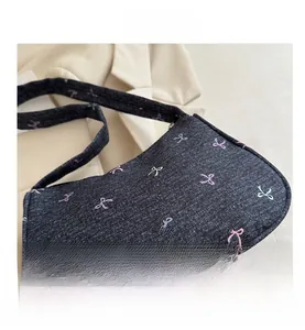 Close-up of blue denim shoulder bag featuring embroidered colorful bow tie patterns