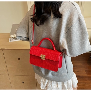 Detail showing red crocodile-patterned crossbody bag with gold buckle on a model