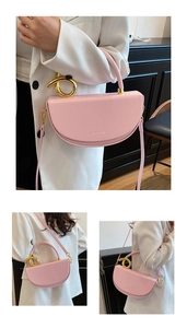 Rosa Satteltasche mit goldenem Griff und Riemen, präsentiert auf weißem Anzugmodell