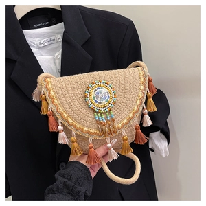 Ethnic straw bucket bag with colorful tassels and embroidery displayed on a black blazer