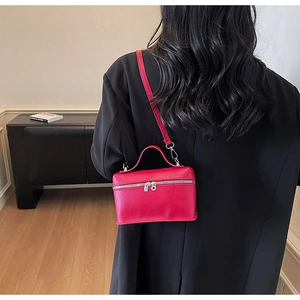 Dettaglio della borsa a tracolla rosso rosa con texture litchi e doppia zip di chiusura