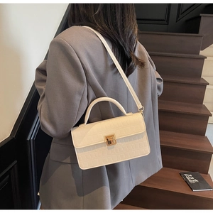 Detail view of cream white croc-embossed handbag with gold buckle on a model