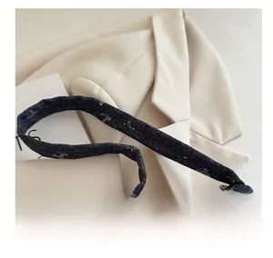 Detail of dark blue denim shoulder bag featuring pink bow patterns and refined stitching