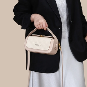 Detail of cream-colored handbag with woven texture flap and gold metallic buckle