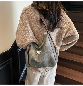 Detail of grey vintage tote bag with brown leather strap and metal triangle emblem
