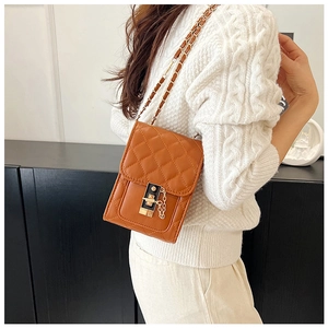 Detail of tan quilted leather shoulder bag with gold metal twist lock and chain strap