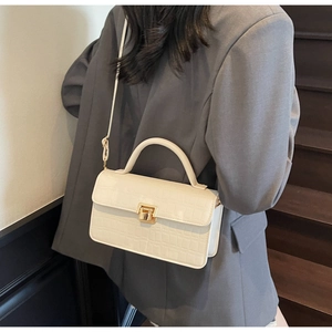 Detail of cream stone texture handbag with gold buckle shown in a lifestyle setting