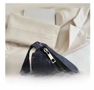 Detail of smooth silver metal zipper on stylish dark blue denim shoulder bag