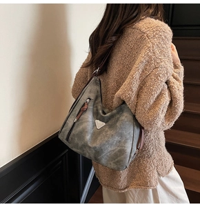 Detail of grey hobo tote with metal triangle accent and side zipper on model shoulder