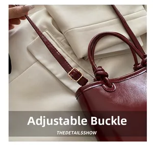 Close-up of wine red patent leather bag with adjustable golden buckle and fine stitching