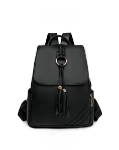 Detailed view of black pebbled leather backpack with gold ring and tassel accents