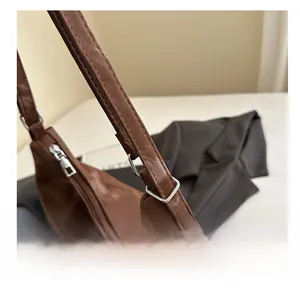 Nahaufnahme der silbernen Schnalle und des verstellbaren Riemens einer braunen Tasche