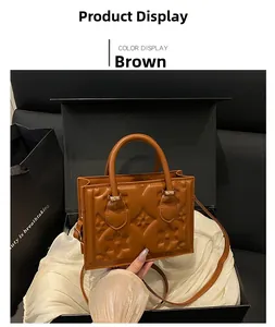Detail of embossed floral leather handbag in brown with gold hardware and top handles