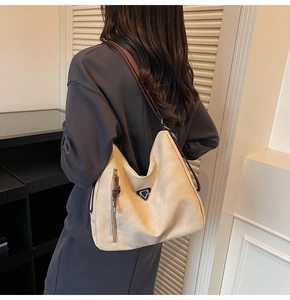 Detail view of large beige tote bag with brown shoulder strap and vertical zipper