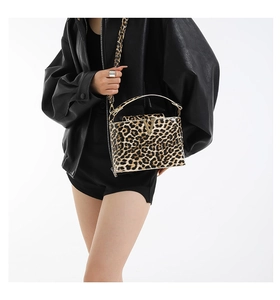 Detail of leopard print handbag with golden V-logo buckle and black jacket pairing