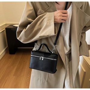 Detail of black pebbled leather box bag with silver hardware and ring zipper puller