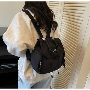 Detailed view of black nylon backpack featuring colorful beads and letter embroidery