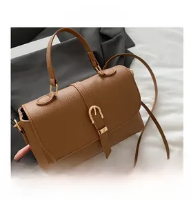 Detailed shot of brown litchi grain leather handbag with gold metal buckle and strap