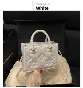 Detail of white handbag featuring 3D floral embossed patterns and golden metal buckles