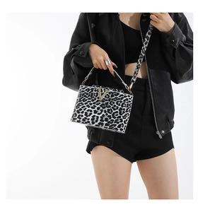 Detail of leopard print crossbody bag featuring a golden V logo and black leather outfit