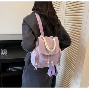 Detail of purple nylon backpack featuring drawstring closure and blue embroidered logo