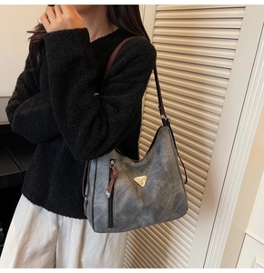 Detail of grey matte tote bag with brown straps and golden triangle metal accent