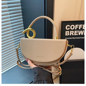 Detail der beigen Satteltasche mit goldenem Metallknoten-Griff und Marken-Schriftzug