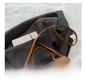 Macro detail of brown litchi pattern leather shoulder bag with adjustable strap and buckle