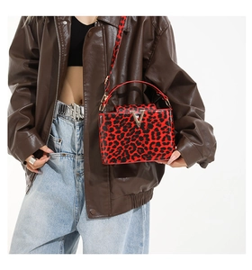 Detail of red and black leopard print crossbody bag with glossy patent leather finish