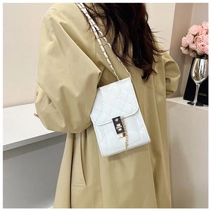 Detail of white quilted crossbody bag with gold chain and clasp on khaki coat