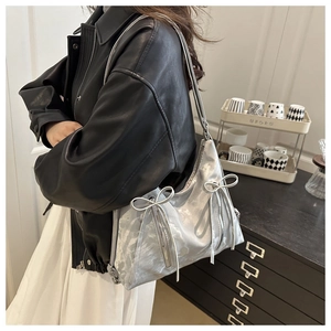 Détail du sac bandoulière argenté métallisé avec des nœuds en ruban et des zips punk en métal