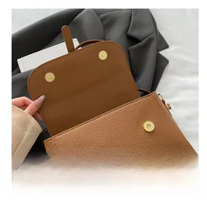 Detail of brown litchi pattern leather bag showing dual gold magnetic snap closures