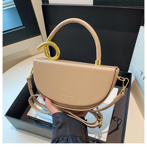 Detail einer beigen halbmondförmigen Handtasche mit gedrehtem Goldgriff und Logo