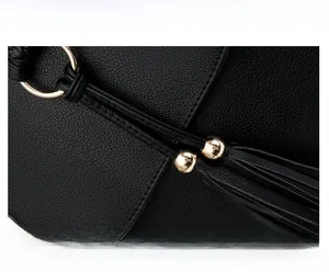 Close-up of black litchi grain PU leather backpack with gold ring and tassel detail