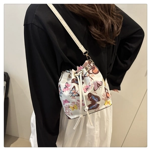 Detail of artistic butterfly print bucket bag with drawstring closure and slim strap