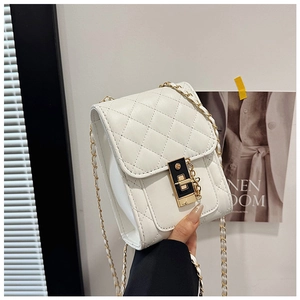 Detail of white quilted crossbody bag with black and gold lock and chain strap