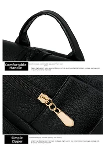 Detail of the black leather backpack featuring wide top handle and gold metal zipper puller
