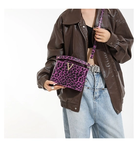 Detail of trendy purple leopard print crossbody bag with golden V-shaped metal buckle