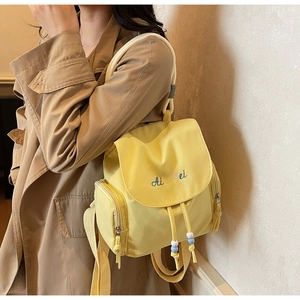 Detail of yellow nylon backpack with embroidered Ai Mei text and drawstring closure