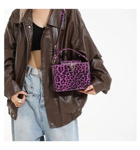 Detail of purple leopard print crossbody bag with metallic V logo and matching handle strap
