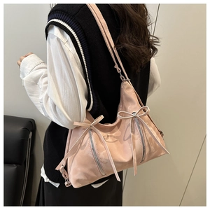 Détail du sac bandoulière rose satiné avec nœuds décoratifs et fermetures éclair argentées
