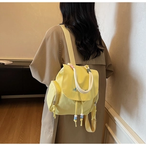 Detail of yellow nylon backpack featuring embroidered Ai lettering and colorful beaded drawstrings