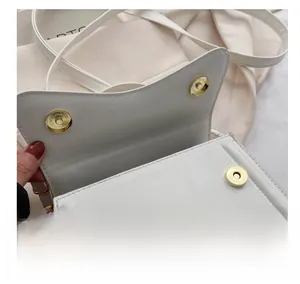Detail view of the white crossbody bag featuring secure dual magnetic snap closures
