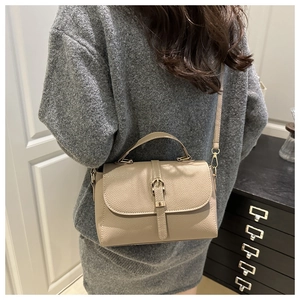 Detailed texture of beige lychee grain leather crossbody bag with gold buckle hardware