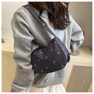 Close-up of dark blue denim shoulder bag with cute pink and white bow embroidery detail