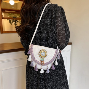Ethnic straw bucket bag with rainbow bead totem and purple tassels in model lifestyle shot