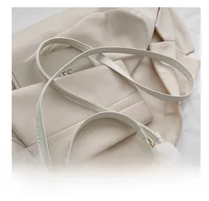 Detail of adjustable white leather strap and gold-tone hardware on minimalist shoulder bag