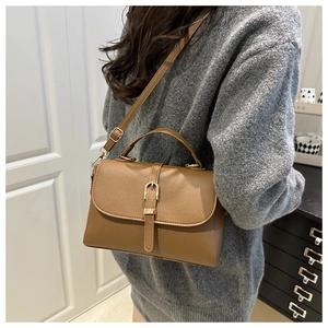 Detailed view of brown lychee grain leather handbag with gold metal clasp on strap
