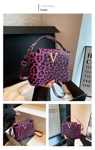 Detail of purple leopard print handbag with golden metal V buckle and textured leather finish